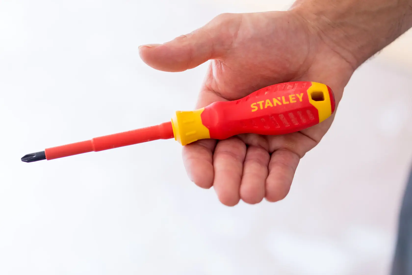 Photo of STANLEY STHT60030-0 red and yellow insulated screwdriver held in hand.