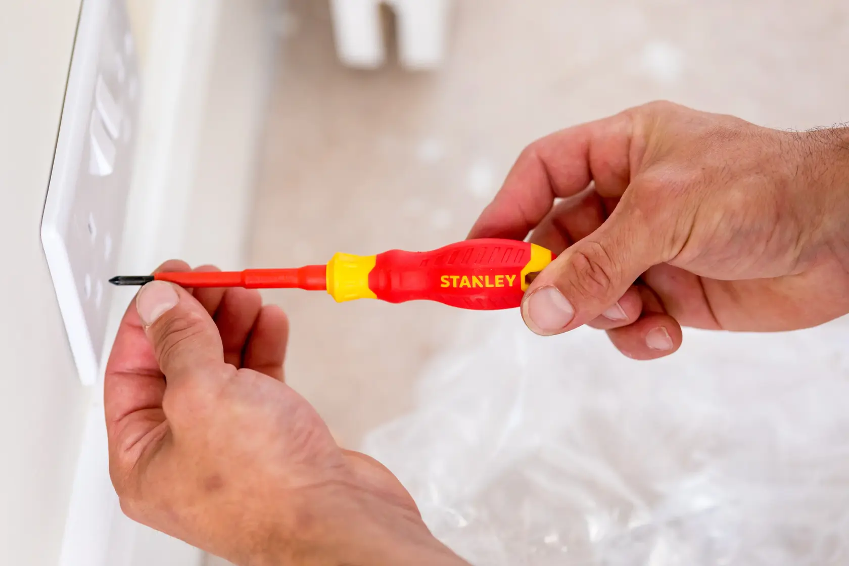 Stanley STHT60032-0 insulated screwdriver used on electrical outlet, close-up photo.