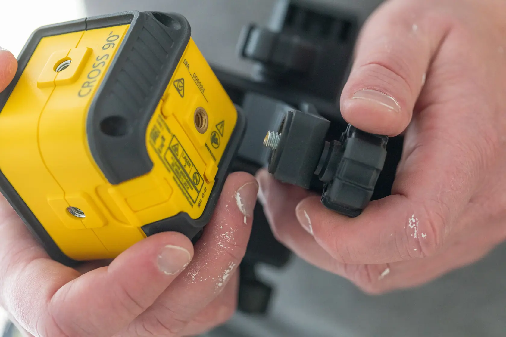 Foto des STANLEY STHT77502-1 Laser-Niveaus, das von Hand eingestellt wird, gelbes und schwarzes Gehäuse, Nahaufnahme.