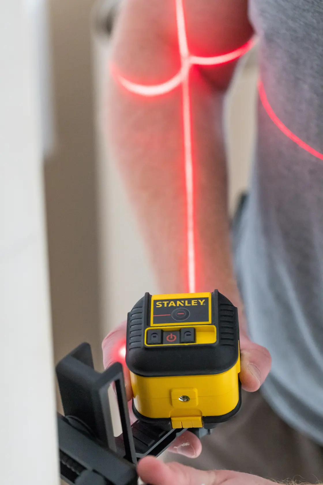 STANLEY STHT77502-1 gelb-schwarzer Kreuzlinien-Laser im Einsatz mit projizierten roten Laserlinien.