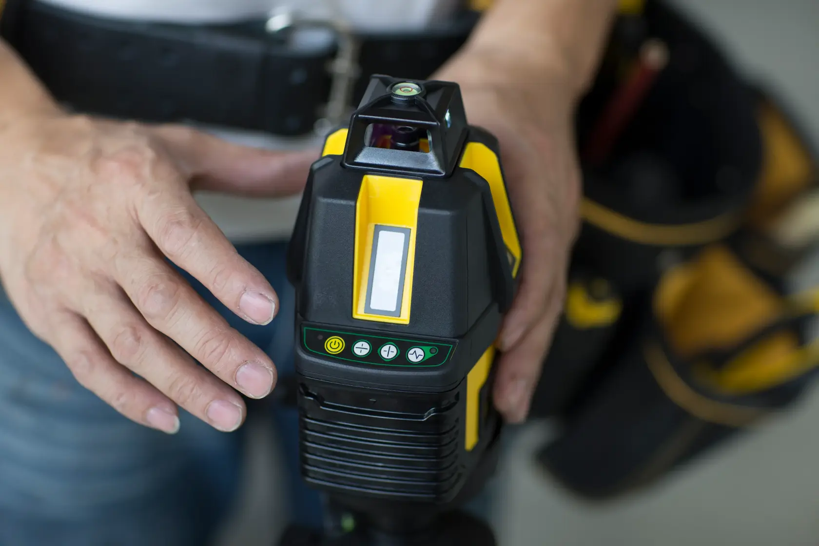 STANLEY STHT77524-1 Laser-Nivelliergerät in der Hand einer Person, Nahaufnahme der Bedienelemente, gelb-schwarz.