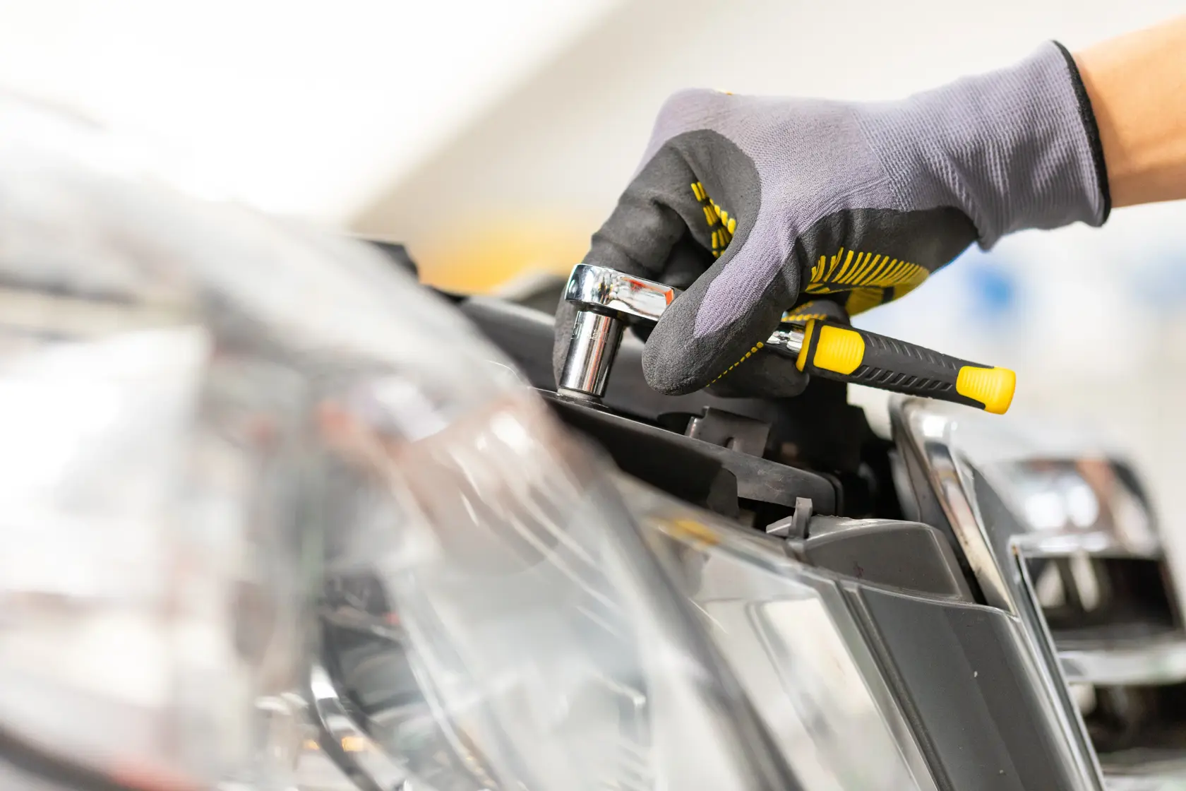 STANLEY STMT86103-0 Ratschen-Schraubenschlüssel am Autoscheinwerfer, Nahaufnahme, behandschuhte Hand, Automobilfotografie.