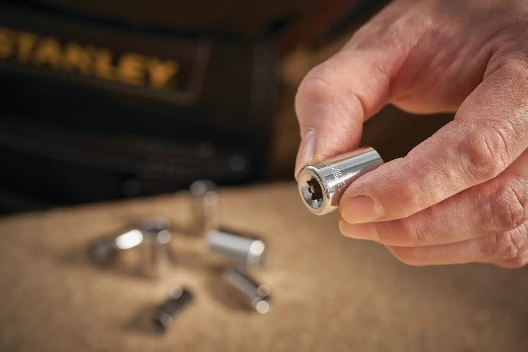 STANLEY STMT86111-0 Steckschlüssel in der Hand, silberfarben, weitere Steckschlüssel unscharf im Hintergrund.