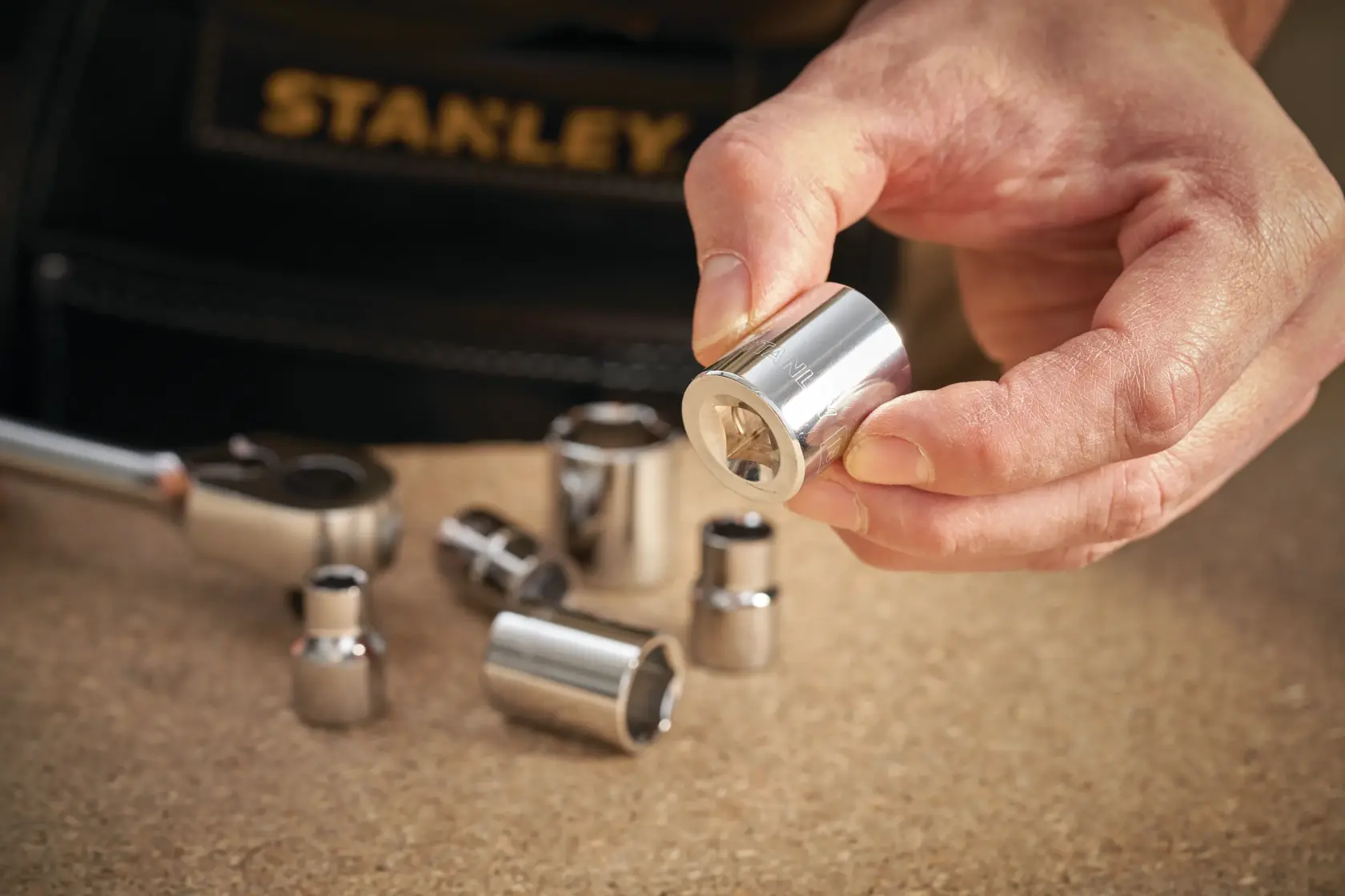 STANLEY STMT86307-0 chrome socket set photography, hand holding socket with tool pouch in background.