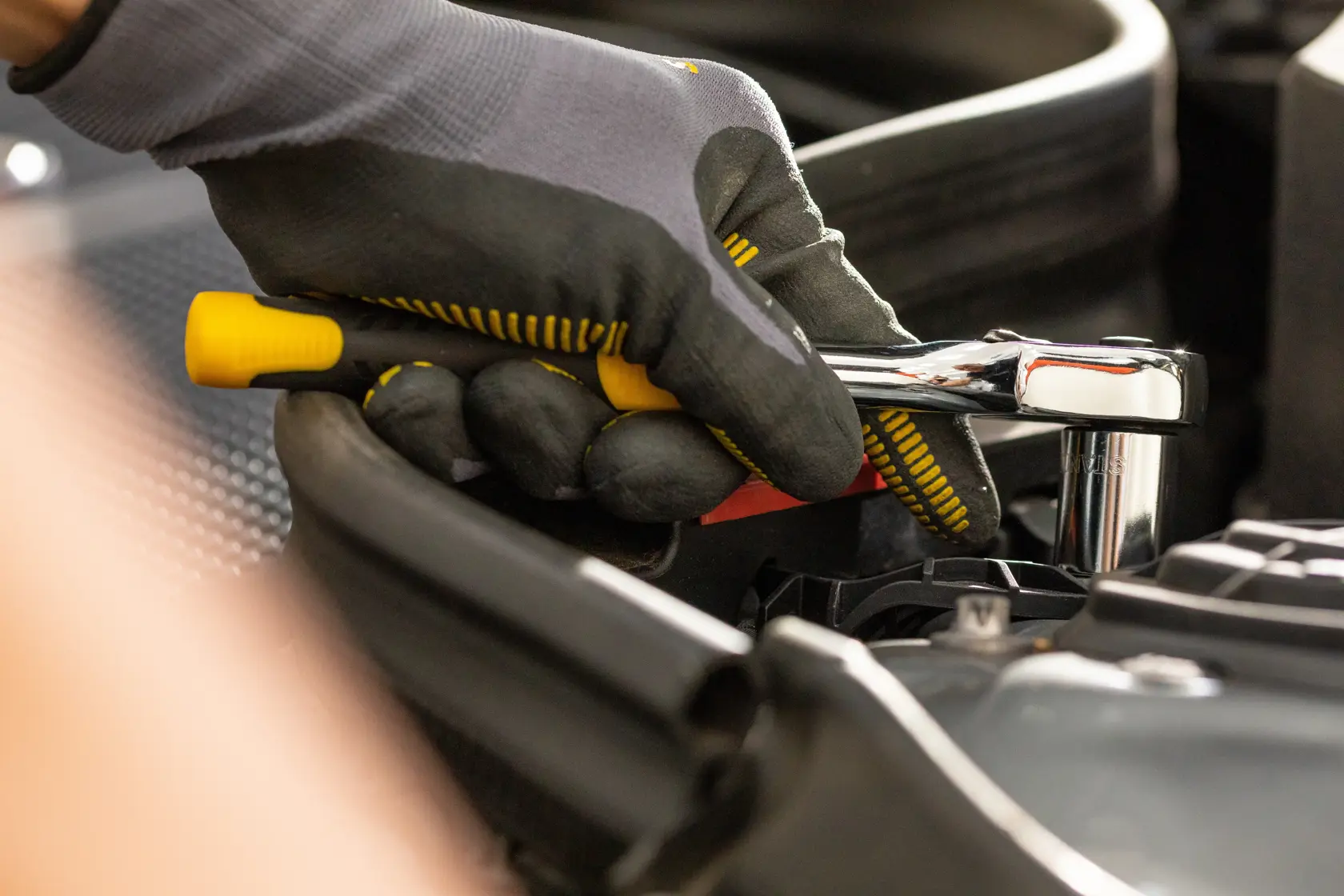 STANLEY STMT86310-0 ratchet wrench in use, close-up of gloved hand working on engine.