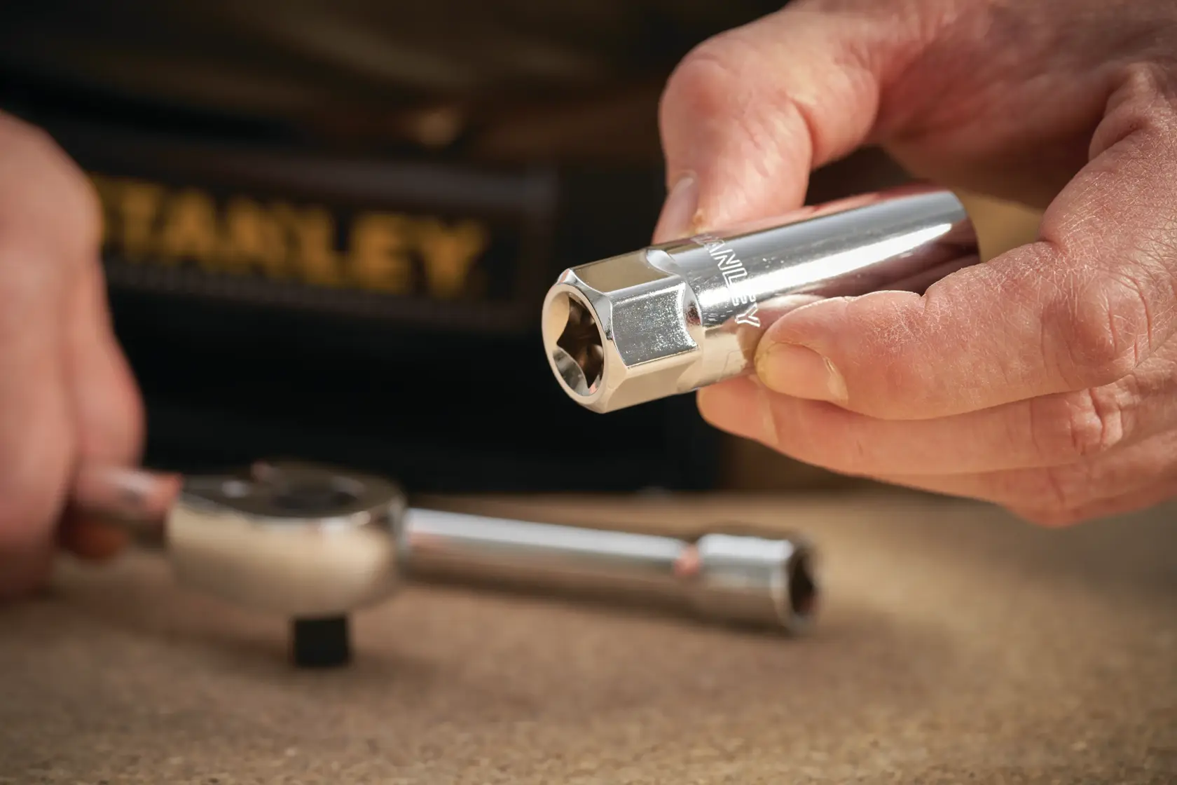 STANLEY STMT88941-0 Steckschlüssel in der Hand, Ratschen-Schlüssel auf dem Tisch, Nahaufnahme.