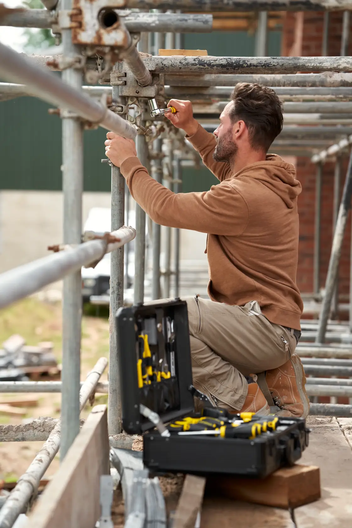 STANLEY STMT98109-1 Wartungskoffer 142PCS geöffnet auf Gerüst mit Arbeiter, der Werkzeuge im Freien nutzt.