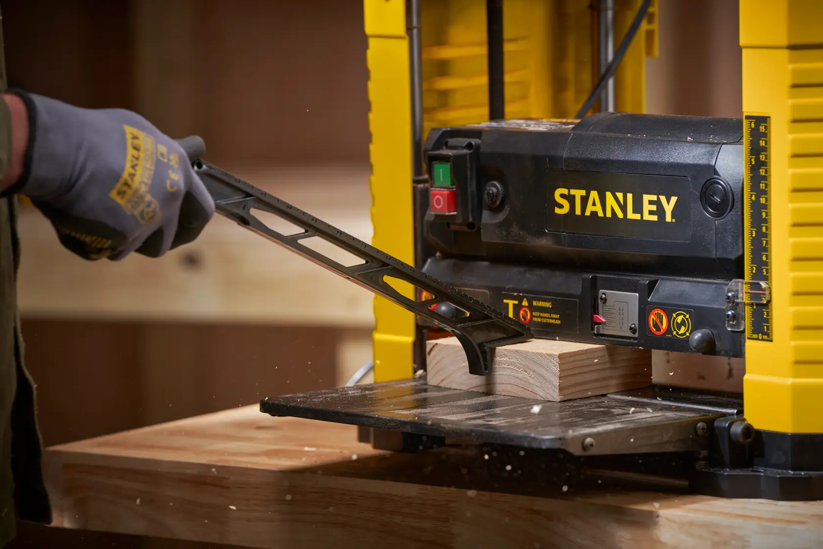 Foto des STANLEY STP18-B2 Hobels im Einsatz, glättet ein Holzbrett in einer Werkstatt aus der Draufsicht.