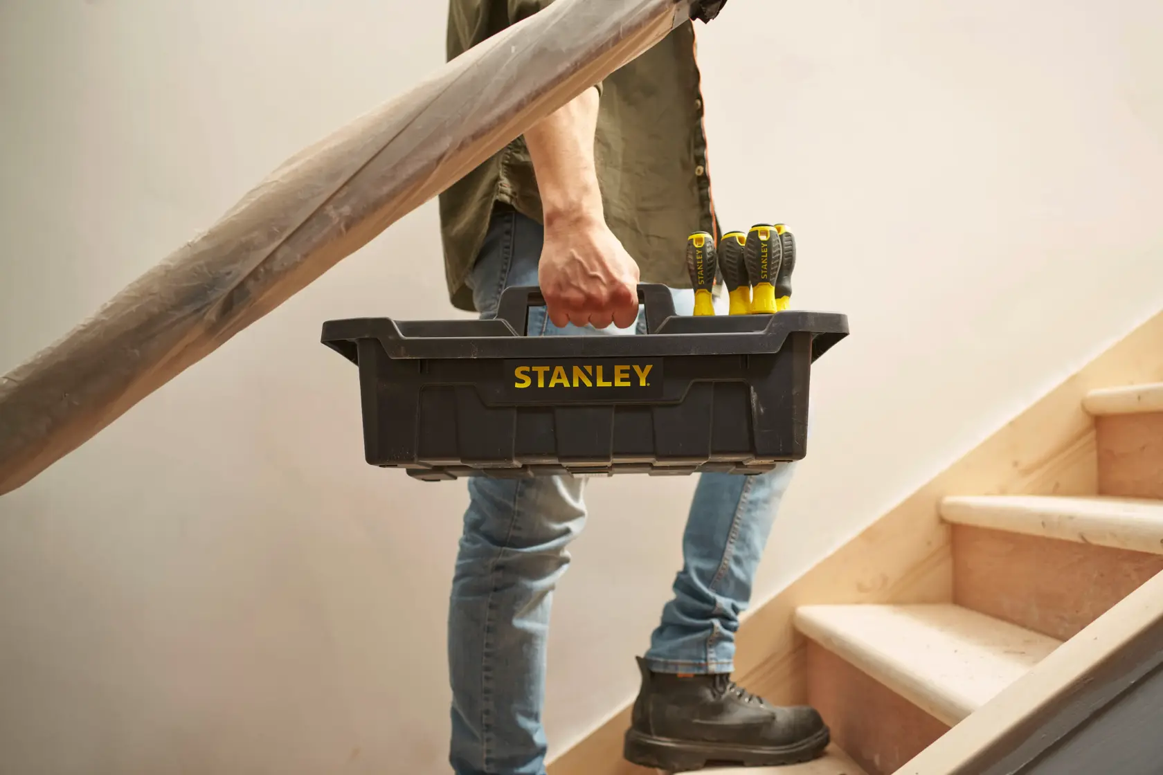 Stanley STST1-72359 schwarzer Werkzeugkasten mit Schraubendrehern, getragen von Person auf Treppe.