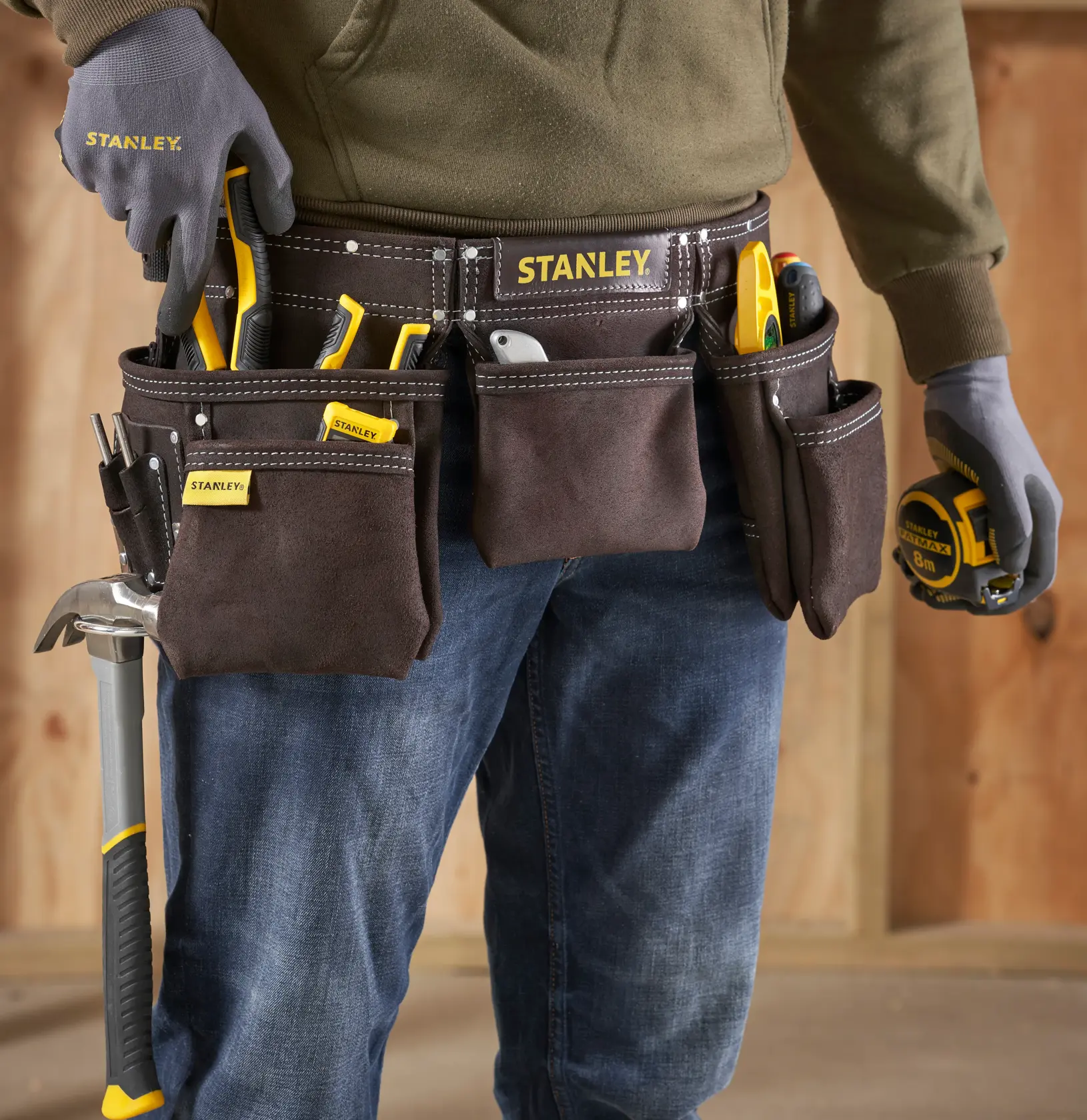 Fotografie des STANLEY STST1-80113 Werkzeuggürtels, brauner Wildledergürtel mit mehreren Taschen und getragenen Handwerkzeugen.