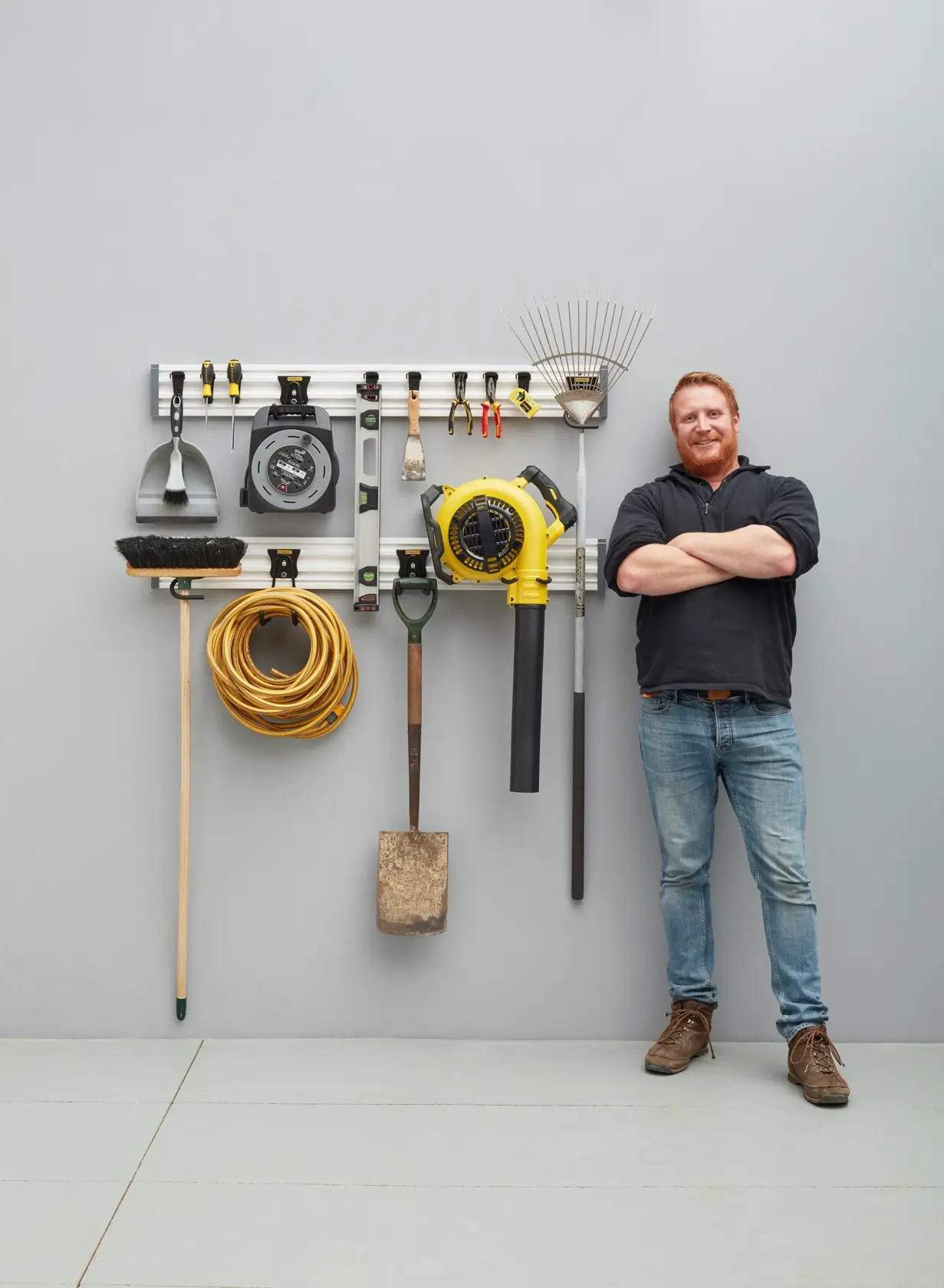 STANLEY STST22000-1 wandmontierter Werkzeugorganizer mit verschiedenen Gartenwerkzeugen und Zubehör in einer Garage.