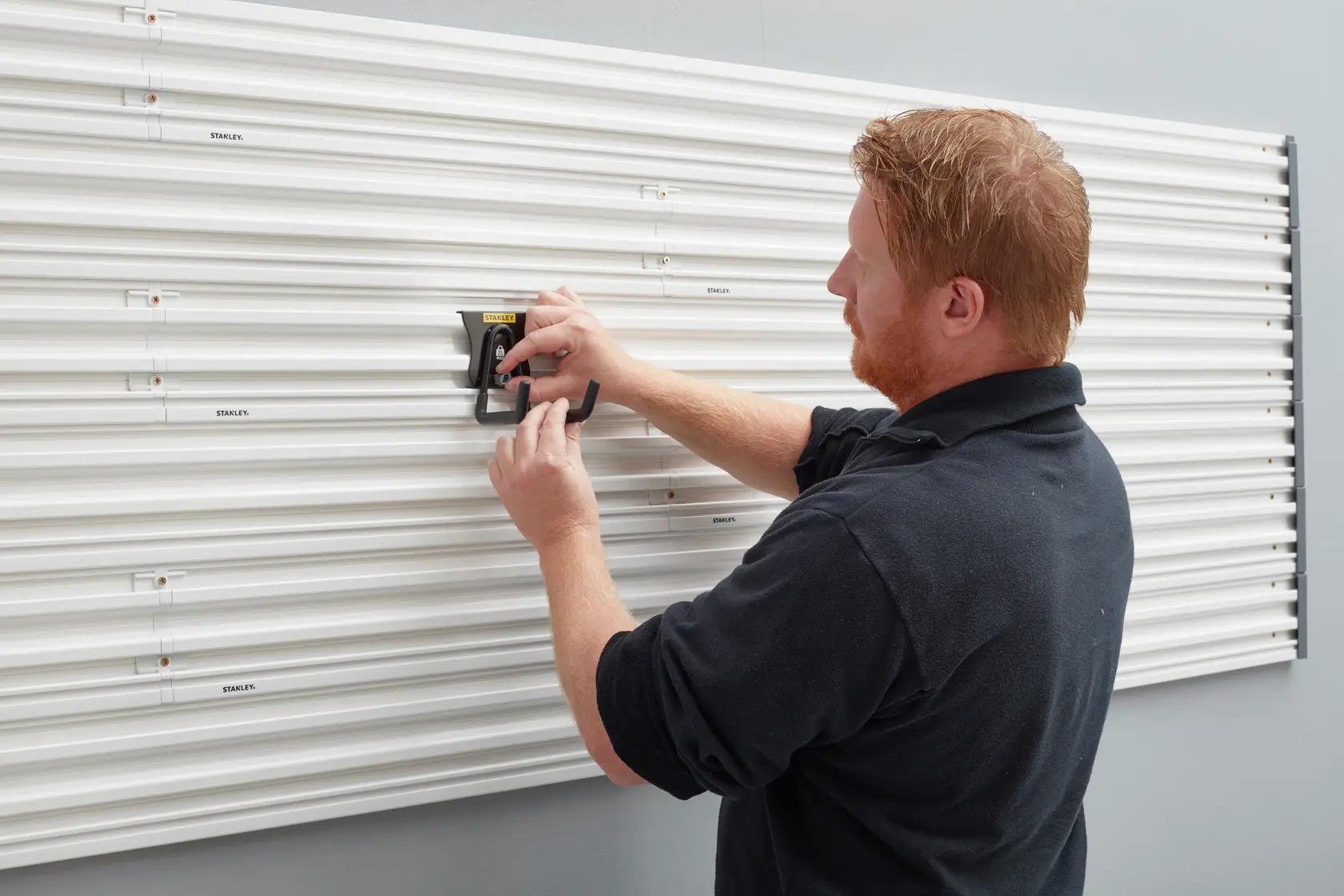 Fotografie des STANLEY STST82607-1 Wandpaneelsystems, montiert von einer Person mit schwarzem Hemd.