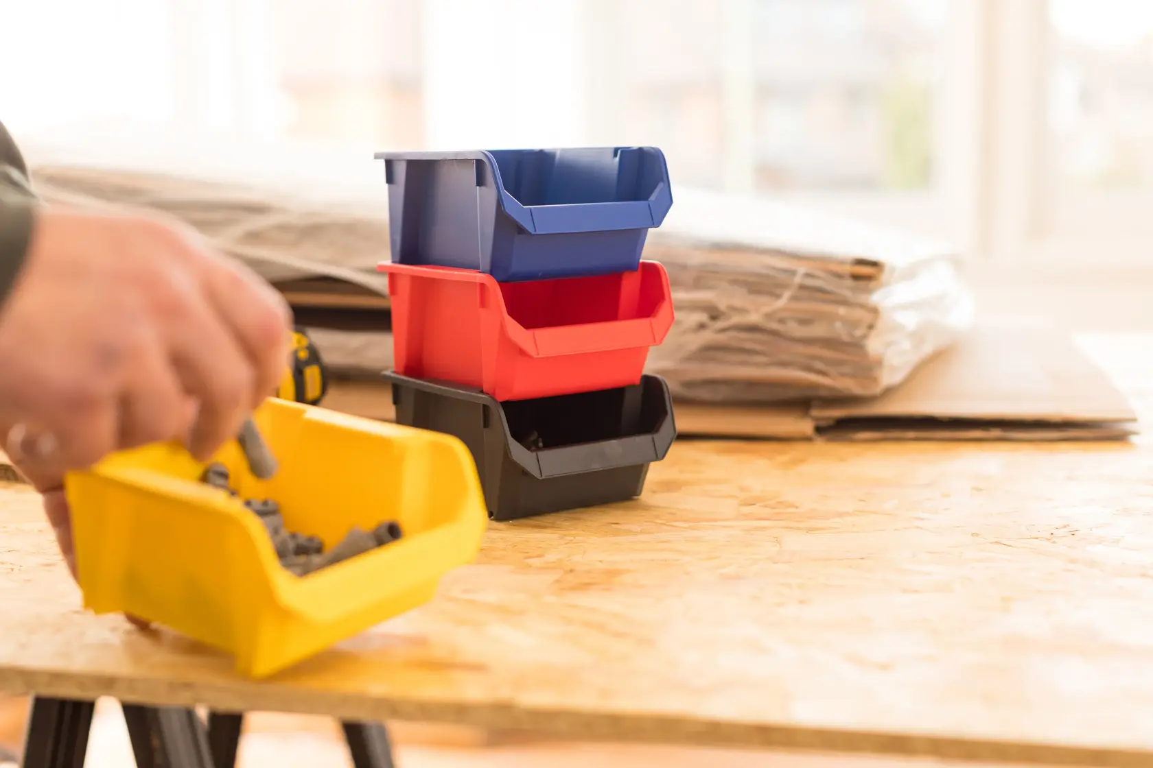 STANLEY STST82737-1 stapelbare Kunststoffbehälter in Blau, Rot, Schwarz und Gelb auf Werkstatttisch.