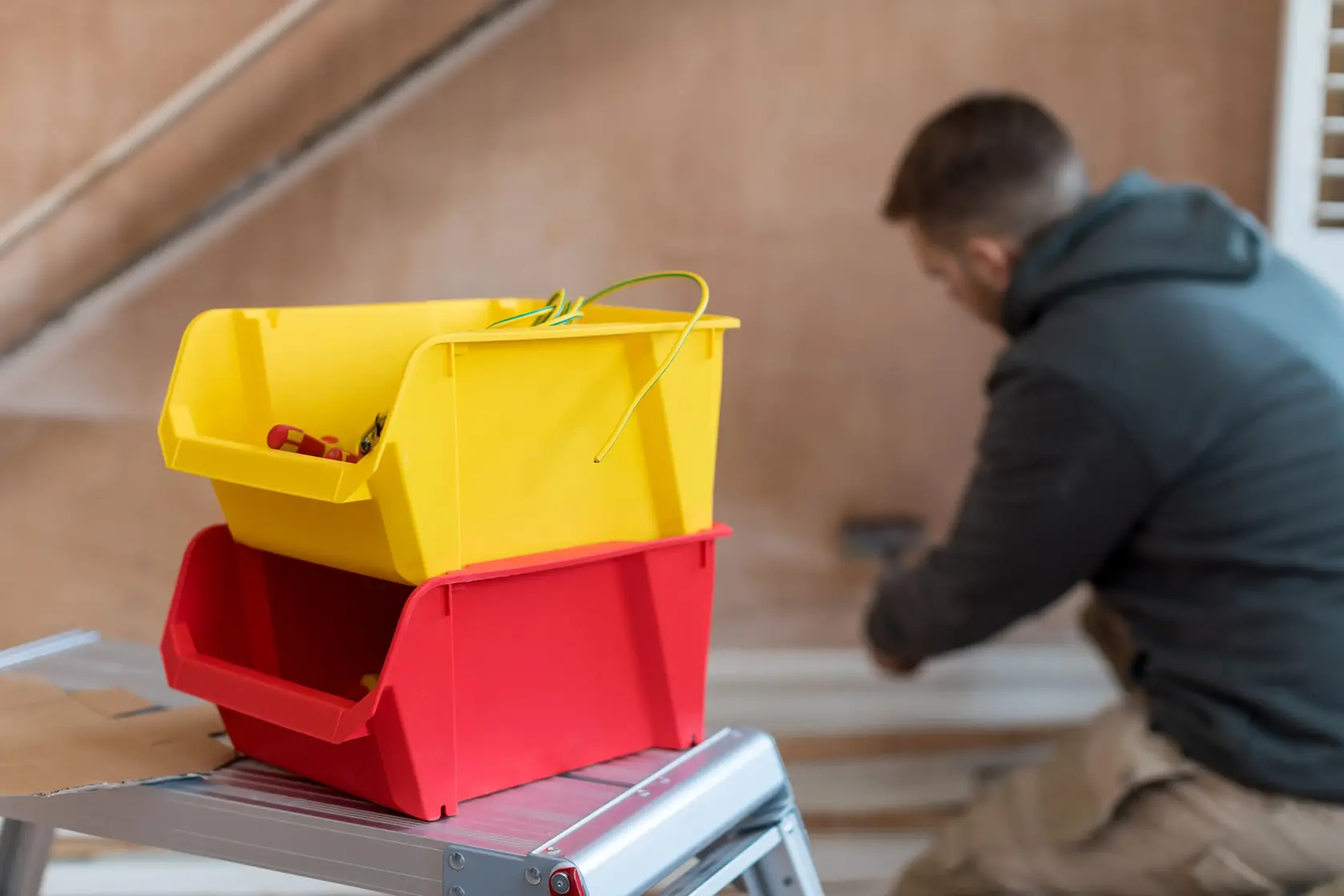 STANLEY STST82742-1 Fotografie gelber und roter Aufbewahrungsboxen auf einer Metallleiter drinnen.