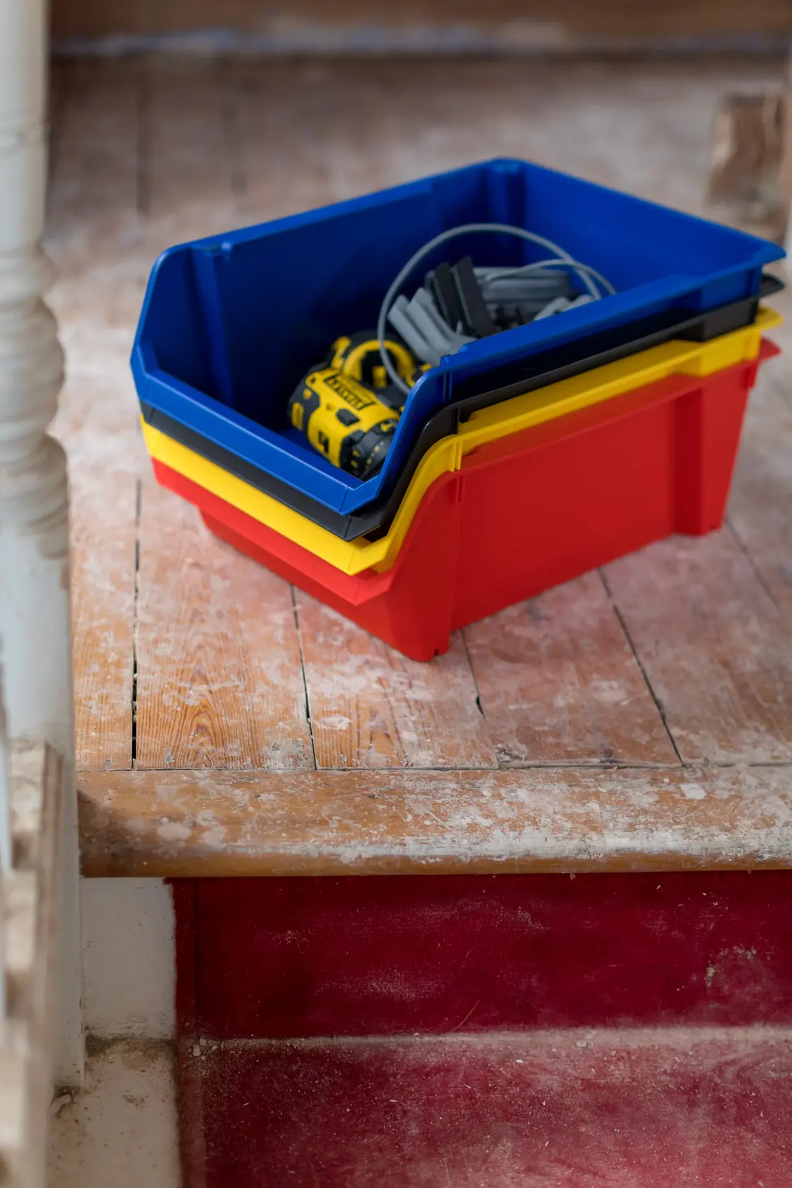 STANLEY STST82745-1 stapelbare Aufbewahrungsboxen in Rot, Gelb und Blau mit Werkzeugen auf Holzboden.