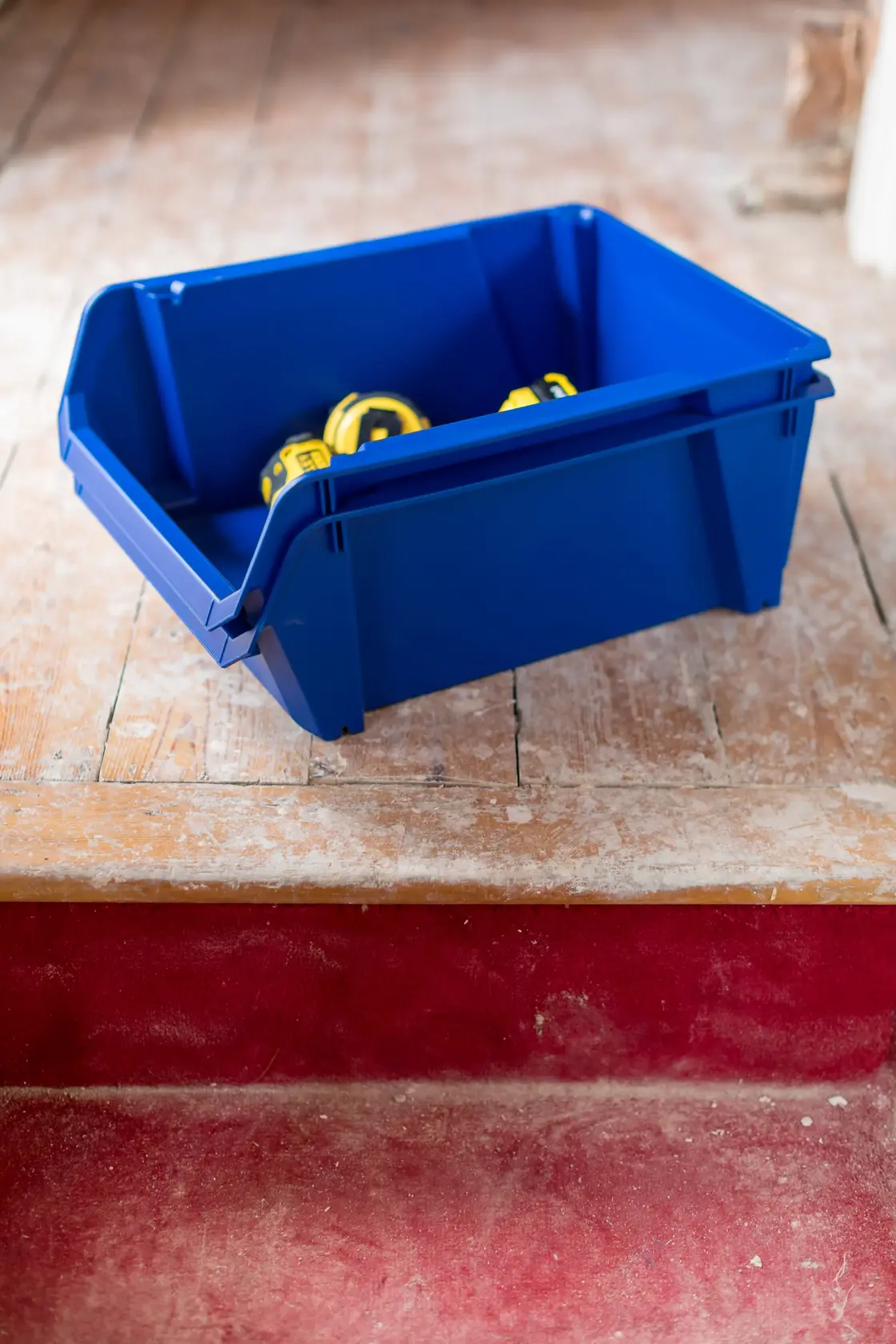 STANLEY STST82746-1 blaue Aufbewahrungsbox mit gelben Maßbändern, schräg auf Holzboden.