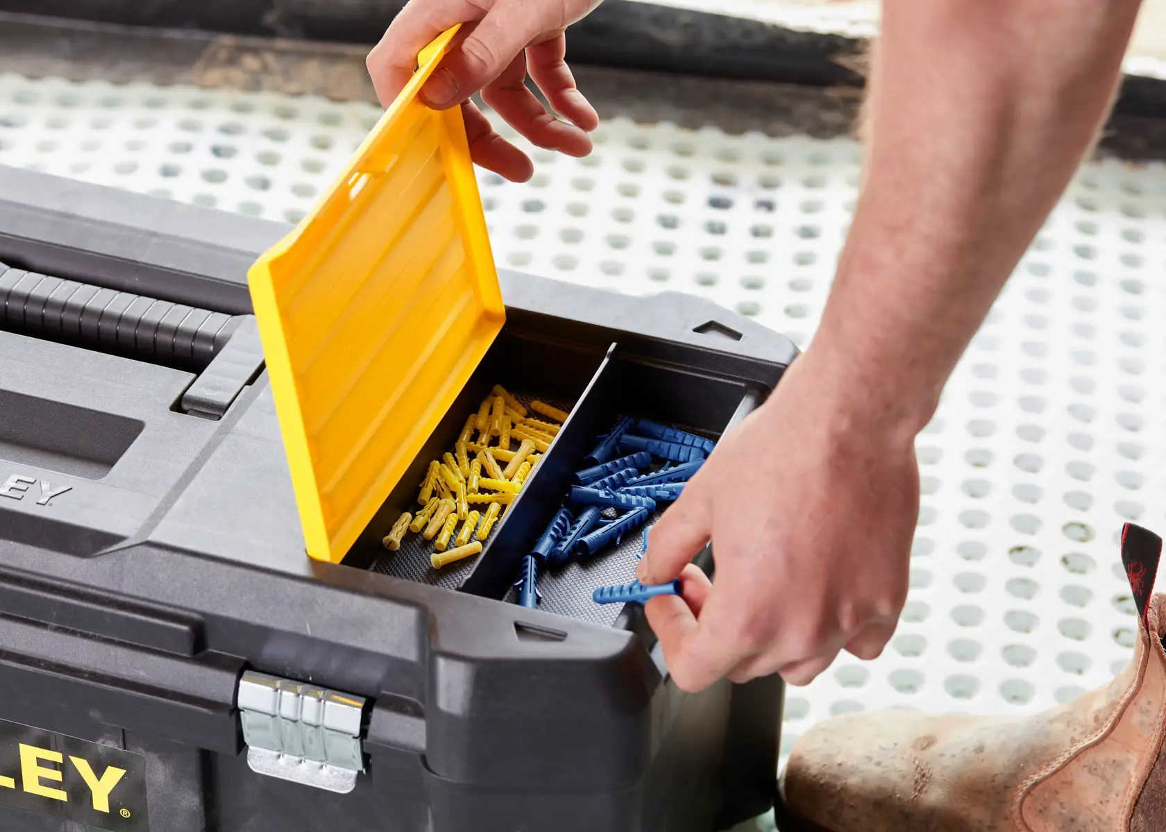 STANLEY STST82976-1 Werkzeugkasten mit offenem gelben Deckel, blaue und gelbe Dübel sortiert.