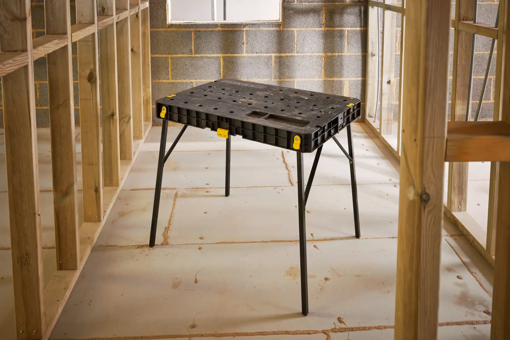STANLEY STST83492-1 Werkbank, schwarze Kunststoffoberfläche mit klappbaren Beinen, gezeigt in Baustelleneinstellung.