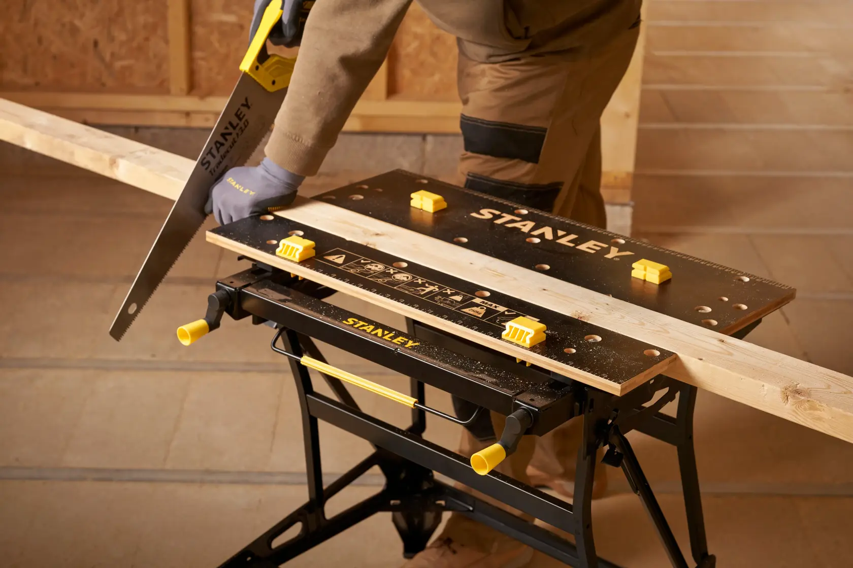 Stanley STST83800-1 Werkbank mit Holzbrett, Handsäge und Person beim Sägen in der Werkstatt. Produkt Fotografie.