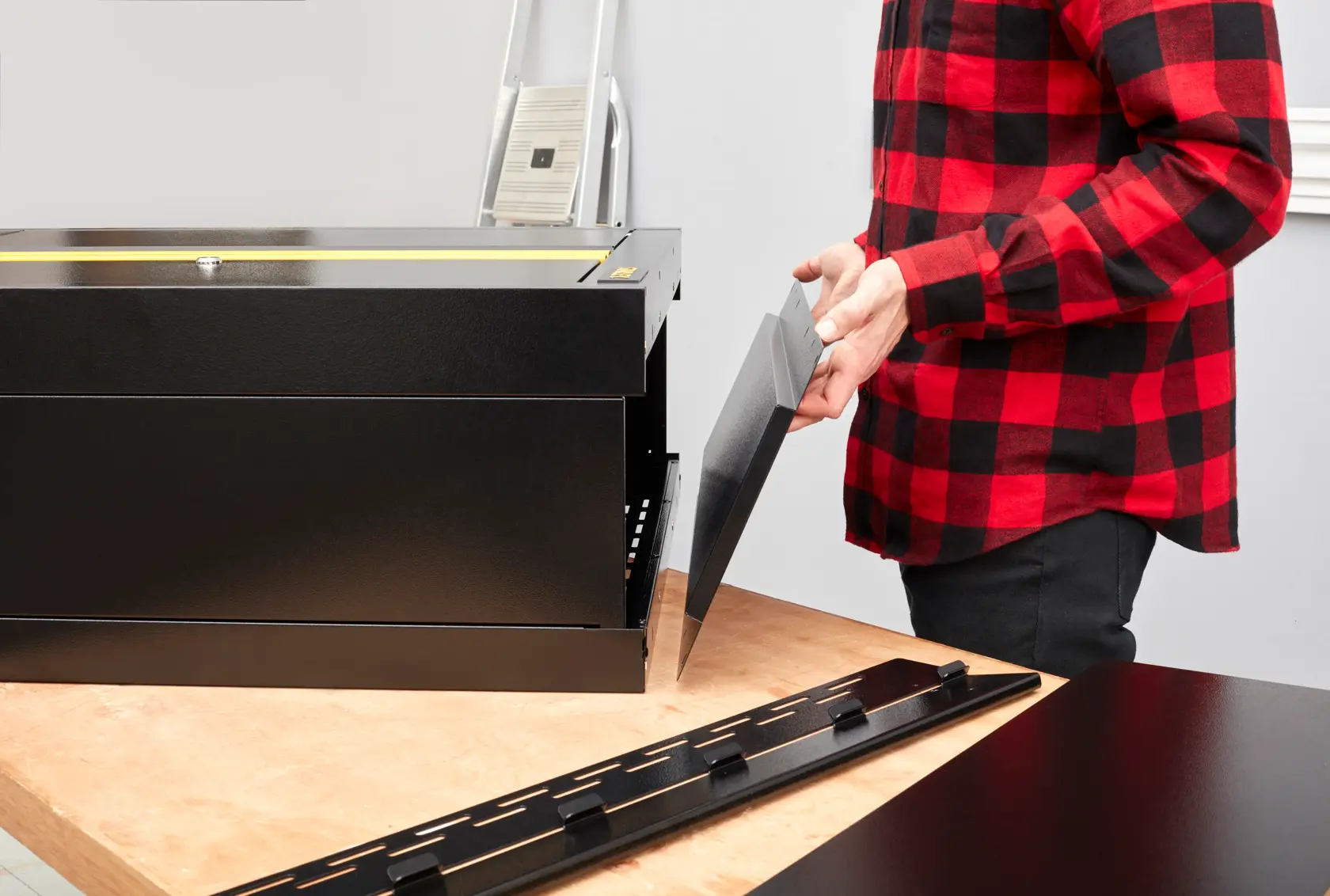 Foto der Montage des STANLEY STST97598-1 Werkzeugkastens, schwarze Stahlplatten auf Werkbank.