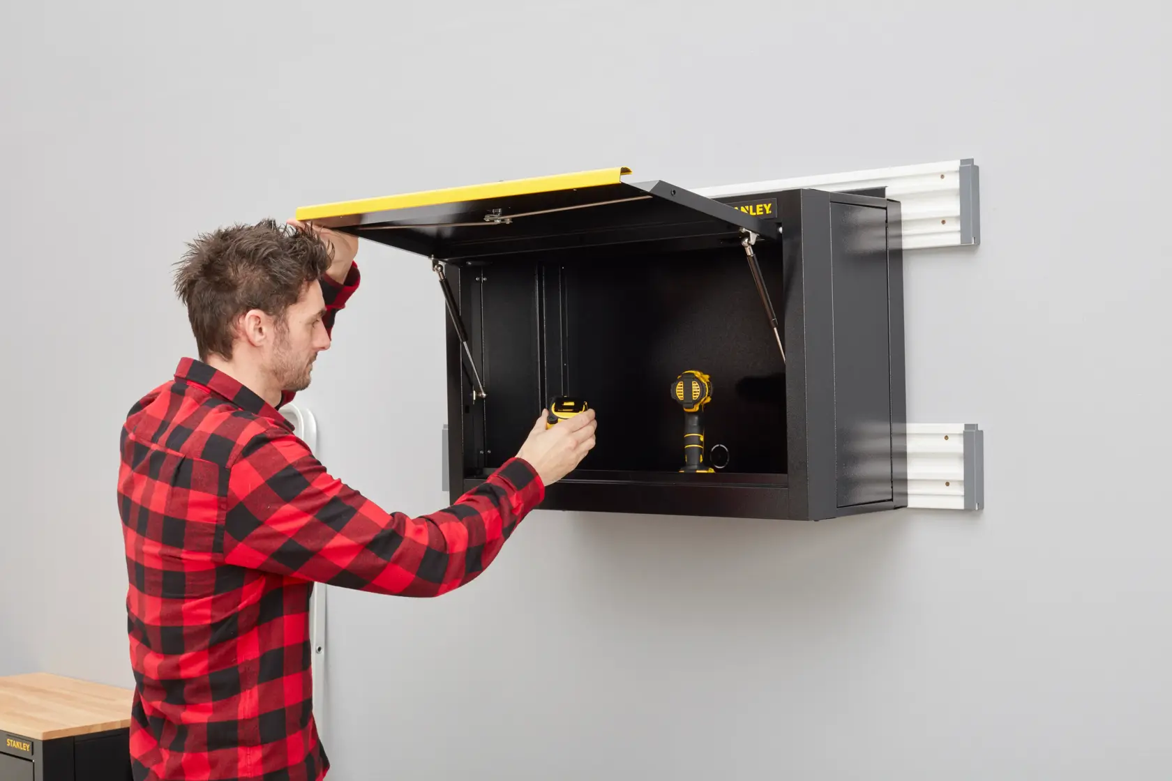 STANLEY STST97599-1 schwarze Wandmontage-Schrank mit gelbem Deckel in Gebrauch, Fotografie Seitenansicht.