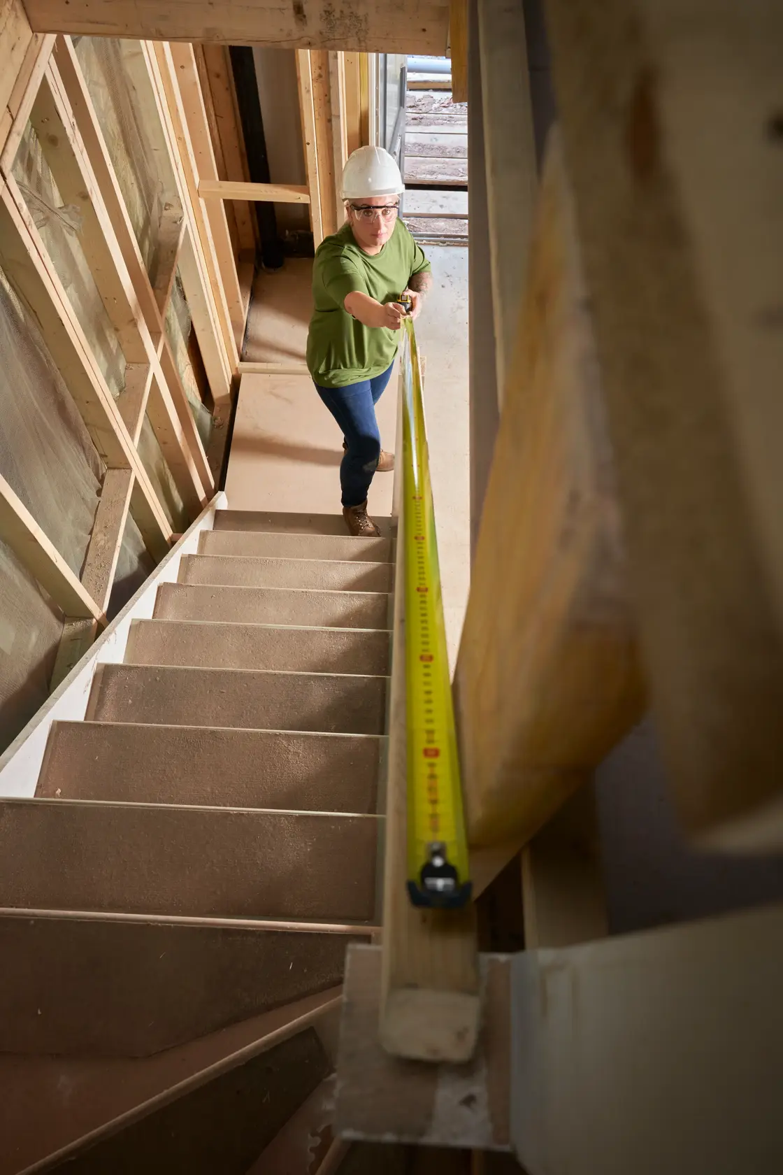 STANLEY XTHT0-33501 Maßband auf Treppe von Person mit Schutzausrüstung in Baustelle verwendet.